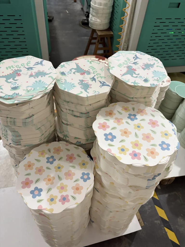 Stacks of finished scalloped paper plates in dinosaur and flower prints